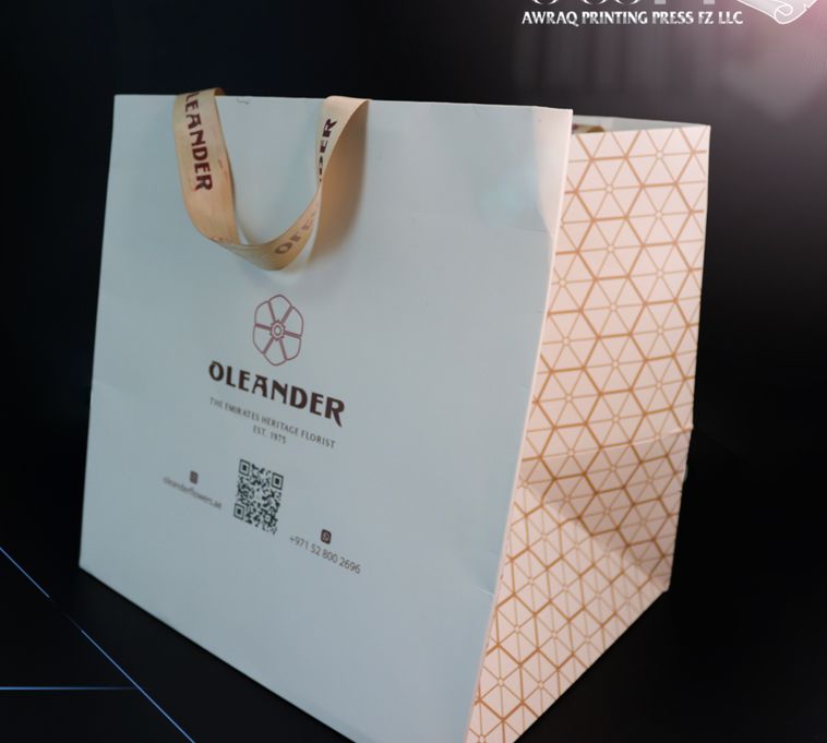White paper bag with ribbon handles and geometric pattern